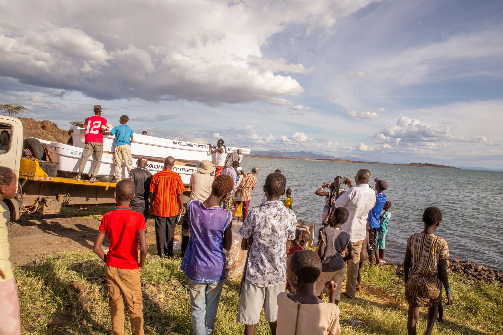 Community members and belongings gathered near the shore for an event.