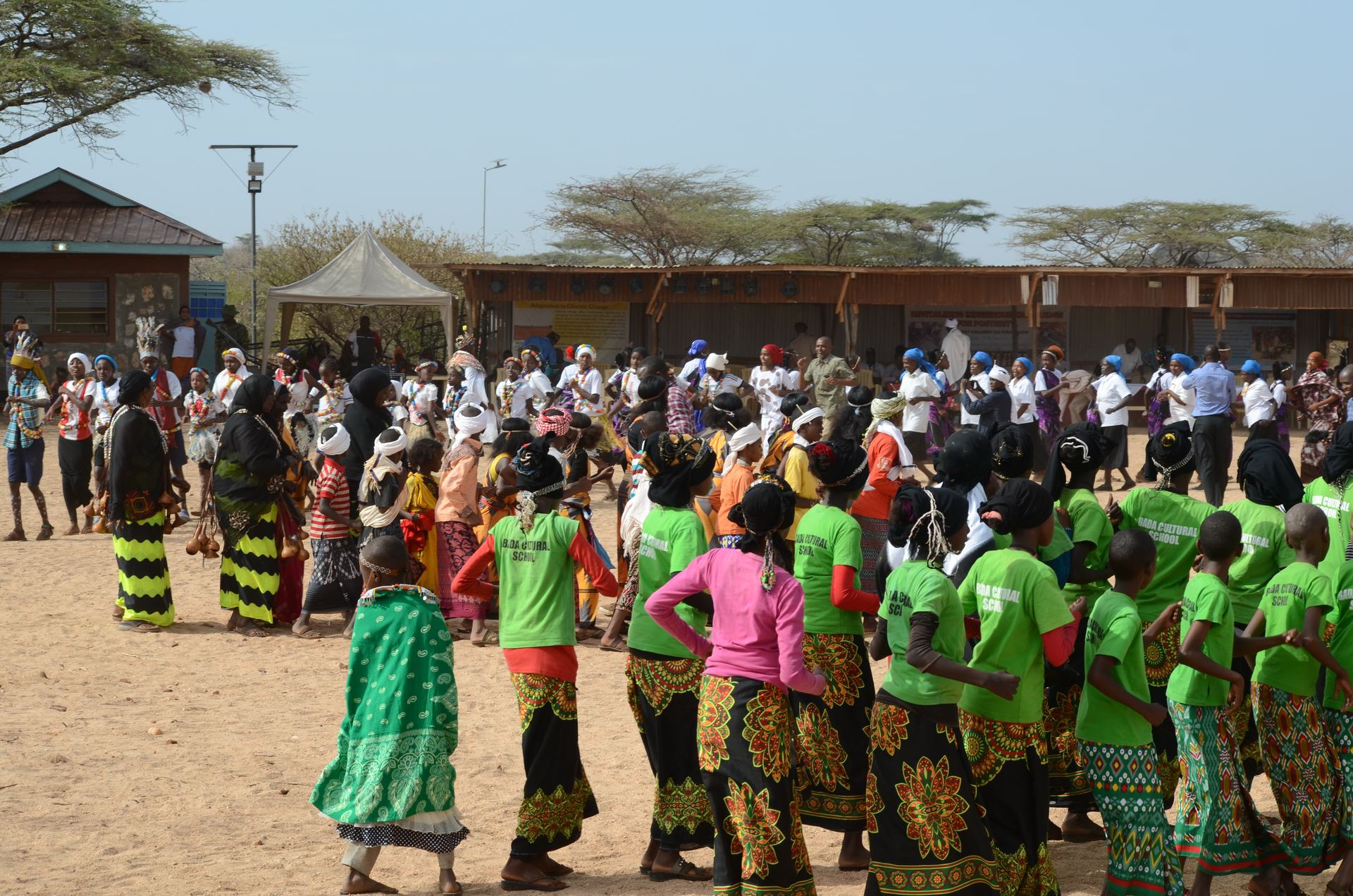 A community gathering seated on woven mats.