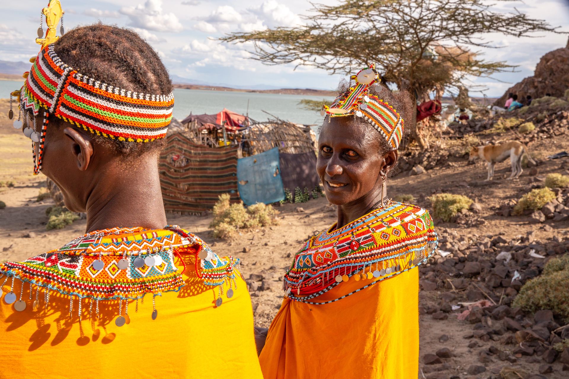 Two women in orange beaded traditional dress.